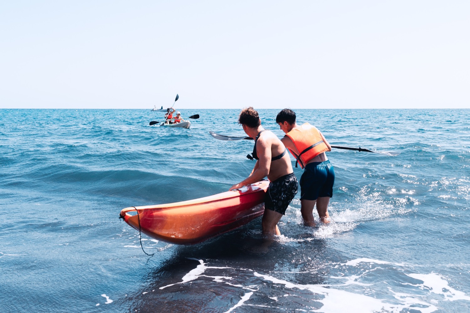 Gruppe von Jugendlichen bringt die Kajaks in Puerto Naos, La Palma, ins Wasser